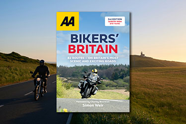 AA Bikers' Britain 3rd edition against a background image of a motorcyclist riding along a road at sunset.
